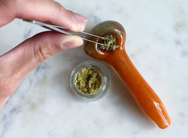 A Hand putting Kief on a Bowl of Flower