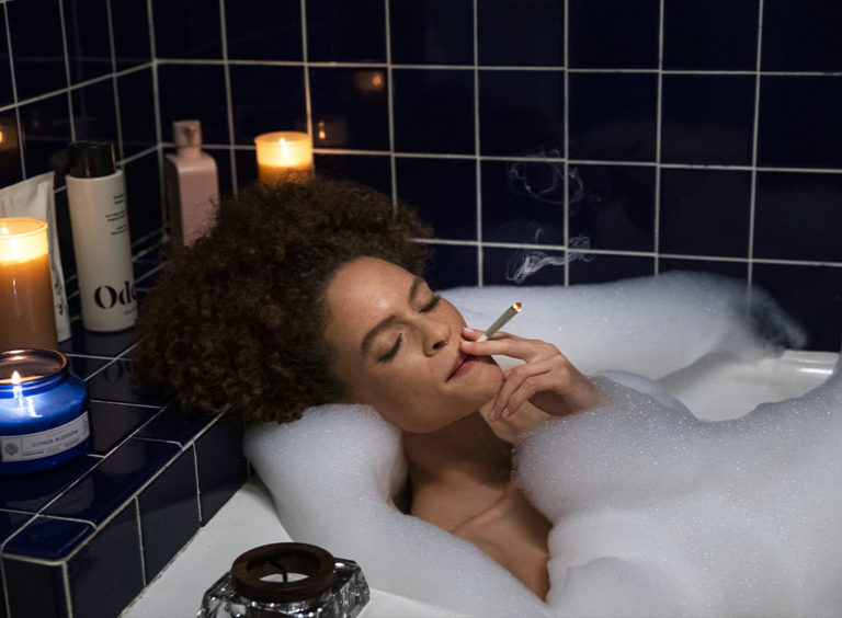 A beautiful woman smoking an INSA cannabis joint in a bathtub