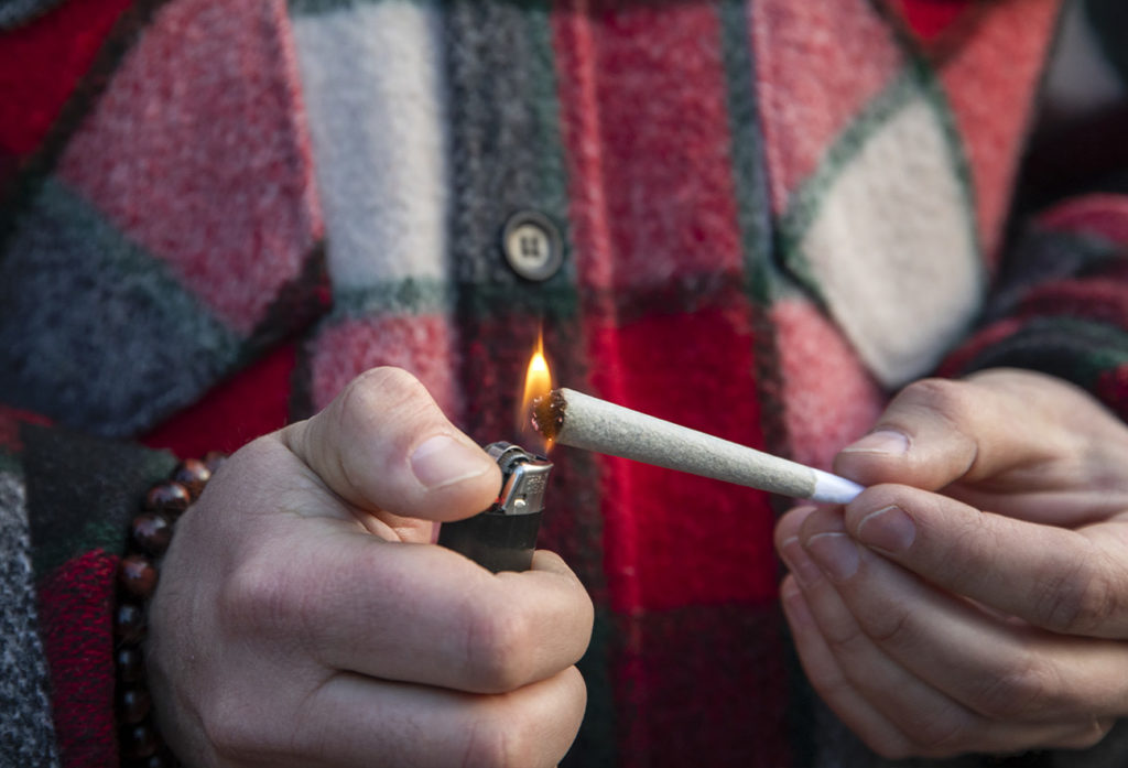 A man lighting a pre-roll cannabis joint with a lighter