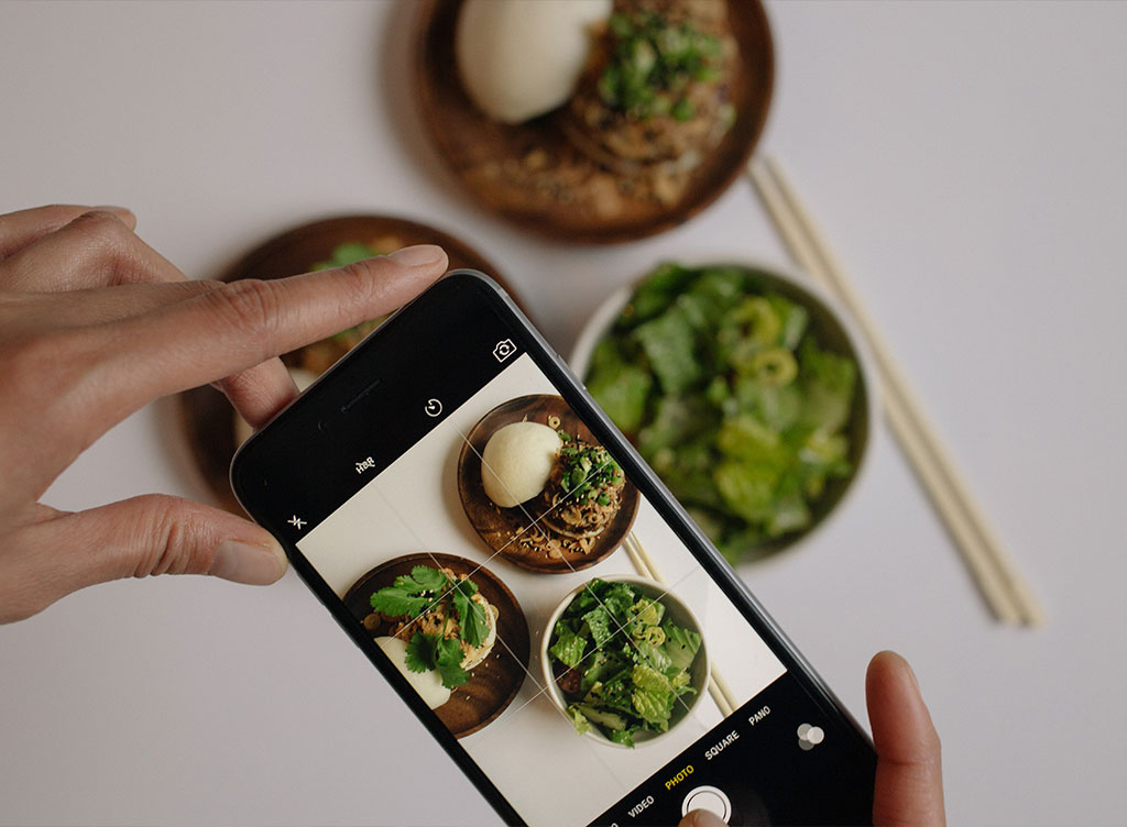 Someone photographing food and chop sticks with a cell phone