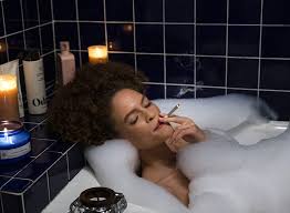 A beautiful woman smoking an INSA cannabis joint in a bathtub