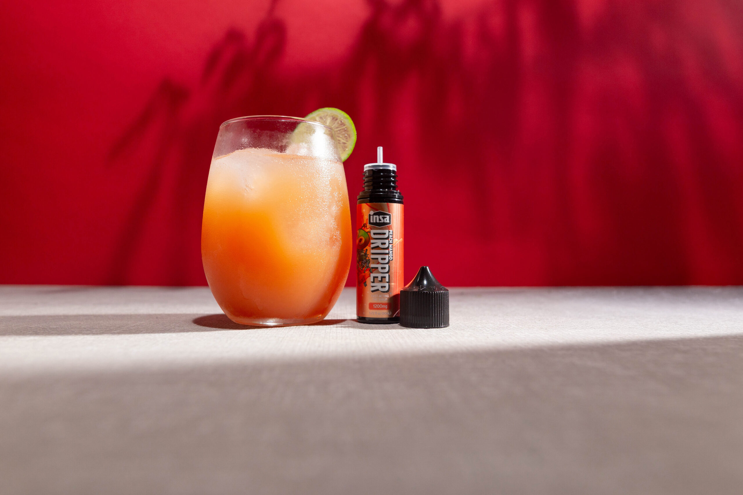 A Peach Grapefruit Fizz drink next to a bottle of Peach Mango Drippers